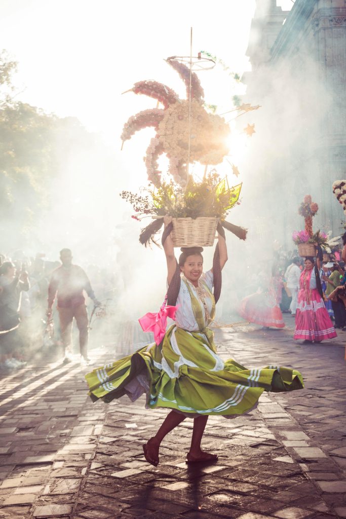 A woman in traditional attire dances joyfully during the Guelaguetza festival in Oaxaca, Mexico.